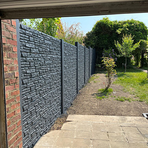 Clôture béton aspect pierre anthracite installée dans un jardin résidentiel
