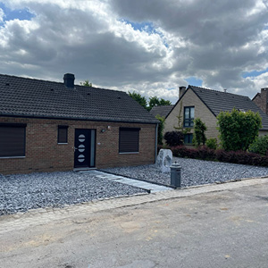 Aménagement extérieur avec allée en graviers et pierre décorative devant une habitation