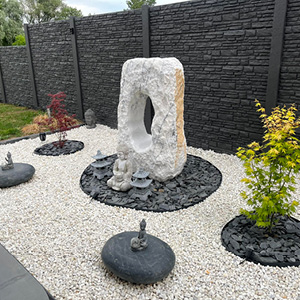Jardin minéral avec sculpture en pierre naturelle et clôture béton décorative